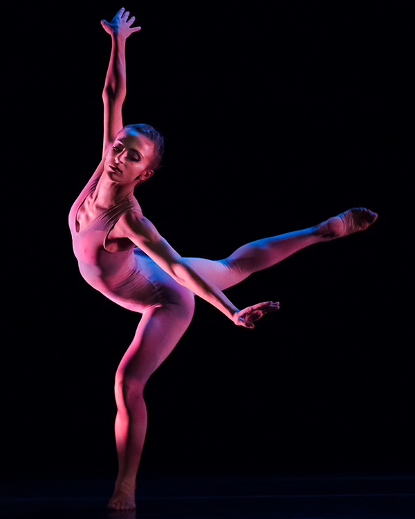 the female dancer shortens her original arabesque position bending both legs and leaning towards the audience, eyes closed